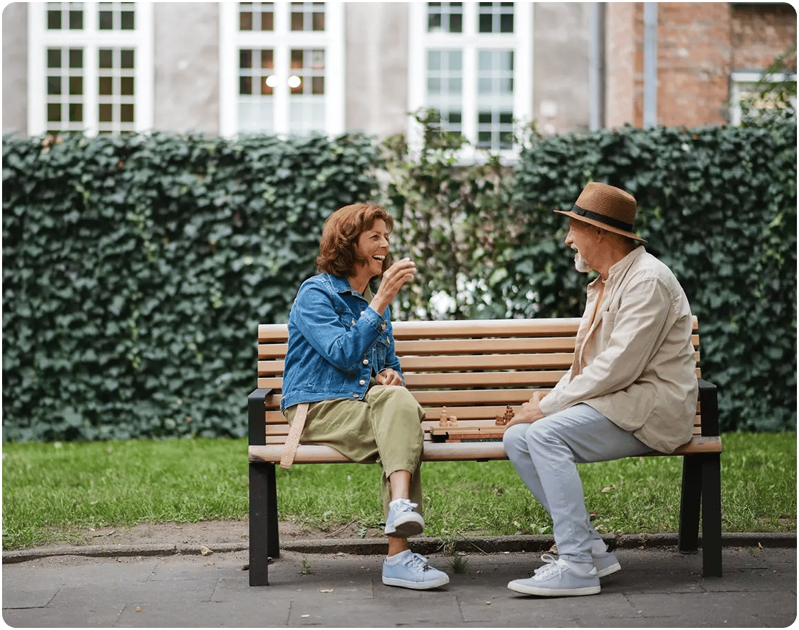 Older man and younger woman talking on bench. 