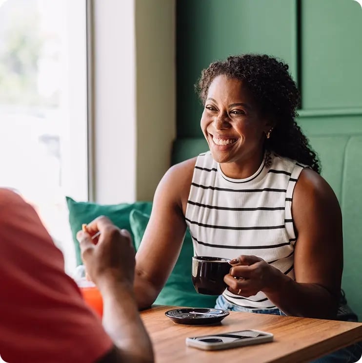 Woman talking to someone at a table. She is smiling. 