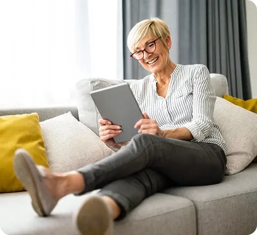Woman sitting on couch on a tablet. 