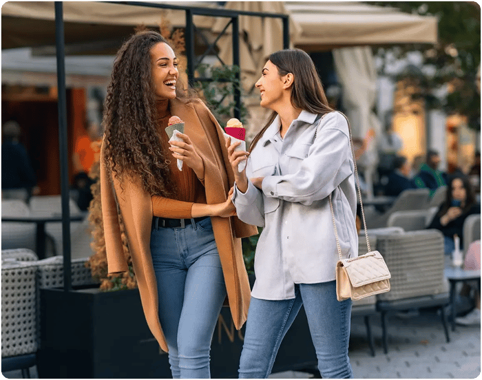 Two girls walking with ice cream.